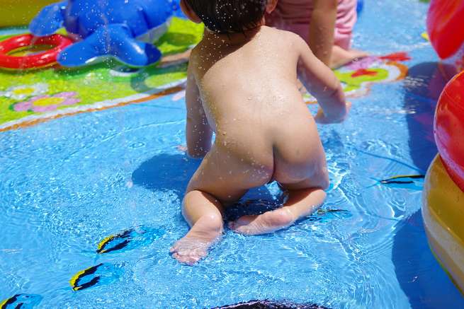 子供用プールに入っている赤ちゃんの裸の後ろ姿の写真