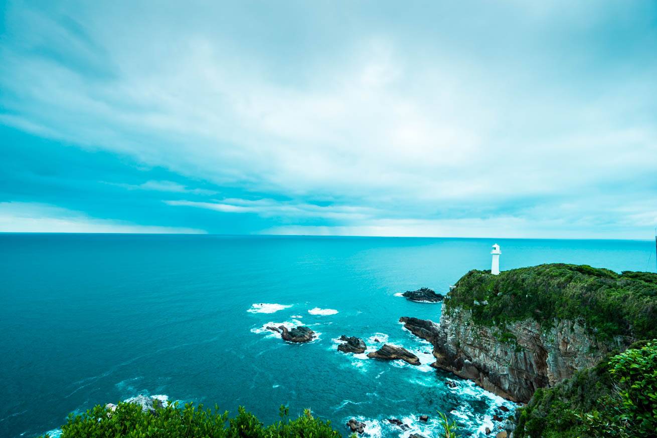灯台の立つ絶壁・青い海・空が広がる足摺岬からの眺望の写真
