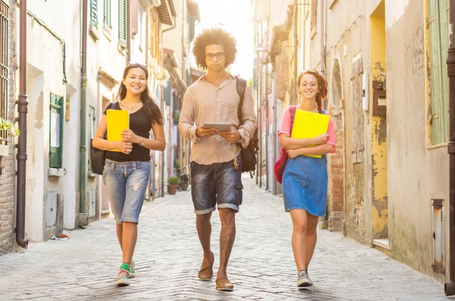 three students walking together in the city center - people and lifestyle concept