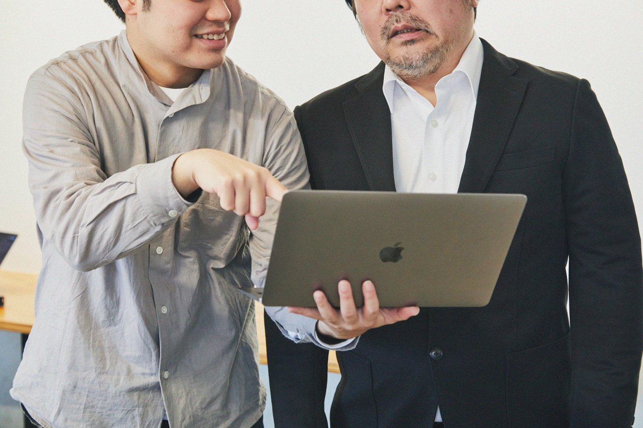 パソコンを見ながら話す2人の男性